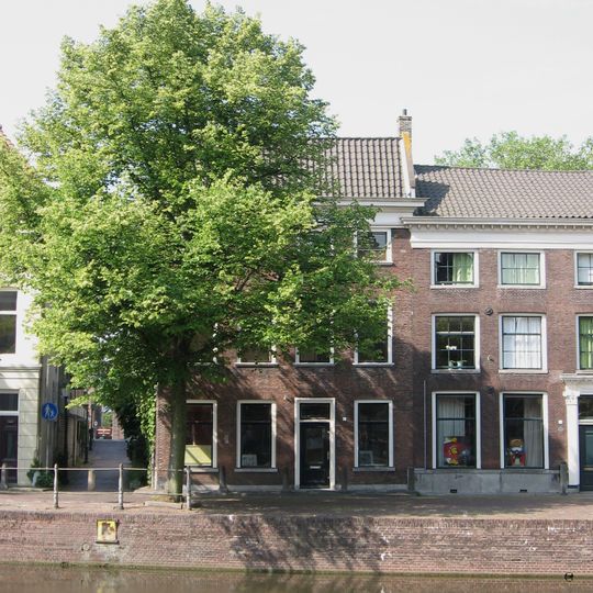 Hoekpand Brandersteeg met bakstenen lijstgevel ter breedte van vier vensterassen. Lage bovenverdieping. Geprofileerde vensterdorpels