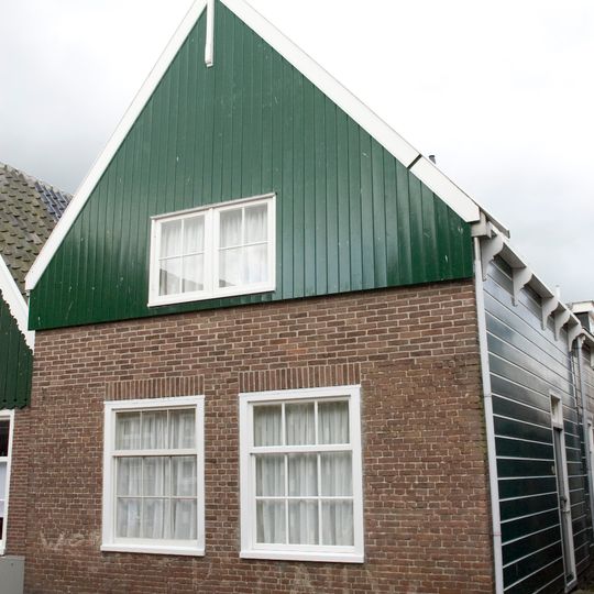 Houten huis met aan de straat een bakstenen pui