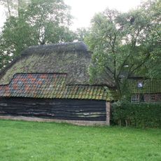 Boerderij onder met riet en pannen gedekt wolfdak. In de voorgevel vensters met luiken en schuiframen met 20- en 25-ruitsroedenverdeling. Deur uit de bouwtijd met eenvoudig bovenlicht