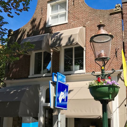 Pand onder zadeldak tegen klokgevel met gebeeldhouwde aanzetkrullen en verhoogde bekroning