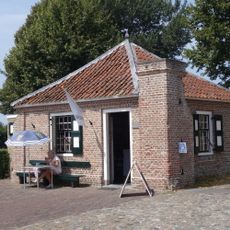 Vierkant gebouwtje op de grens van het kerkterrein, waarin vensters met kleine roedenverdeling