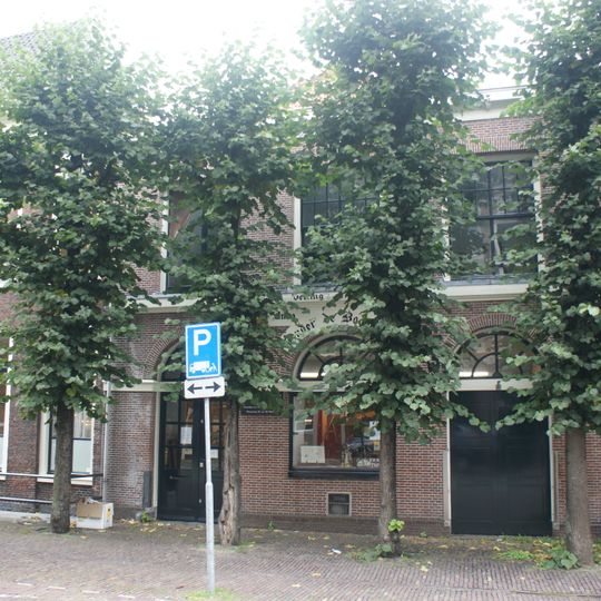 Pand met bakstenen gevel met rechte kroonlijst. "Wijnkoperij de Vier Boompjes". Beneden drie poorten waarvan een als raam dienstdoende