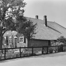 Boerderij met rieten wolfdak en in de zijgevel een stroomlaag. Vensters met luiken en 15- en 12-ruitsramen