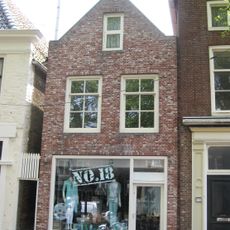 Smal pand onder verlaagd zadeldak tegen topgevel