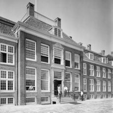 Pand met lange gevel met rechts en links vleugels, gebeeldhouwde middenpartij, mansardedak