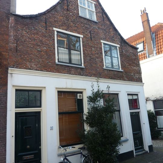 Pand met lage tuitgevel onder gepleisterd sieranker. In geveltop kruisvensters