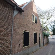 Behoort tot de woning Dekanijstraat 2, is daarvan een vleugel in het L-vormig complex. Zadeldak van rode pannen.