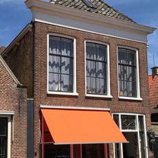 Pand met verdieping en rechte kroonlijst onder schilddak met schoorsteen boven voorschild