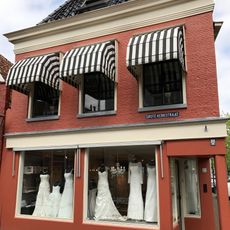 Diep hoekpand tegen achtertopgevel onder zadeldak met aan voorzijde schild met topschoorsteen