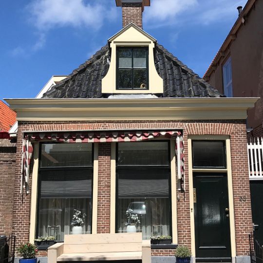 Laag pandje onder schilddak met twee hoekschoorstenen en dakkapel in voorste schild