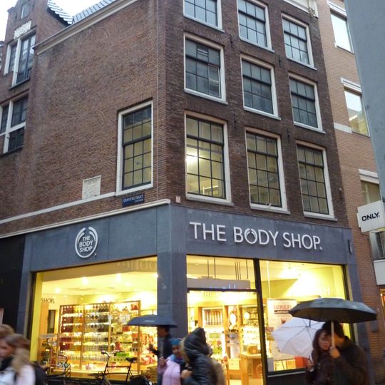 Hoekhuis uit 1561 met voorgevel onder rechte lijst met consoles en hoge gemetselde dakkapel op de zijgevel, waarin gevelsteen