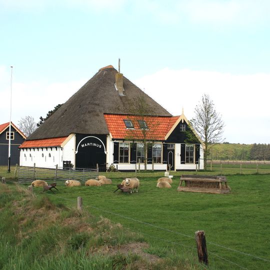 Stolphoeve met inrit opzij van de voorzijde, waarvan het overig gedeelte de woning bevat. Boven de ingang terzijde houten topje; zesruits vensters