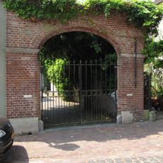 Grote gemetselde poort met pilasters en twee gedenksteentjes