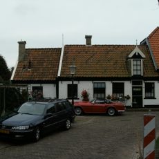 Aardig gelegen laag pand met lange gevel aan de straat, waarboven houten dakkapel