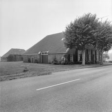 Schuur met gepotdekselde wanden onder een met grijze muldenpannen gedekt schilddak