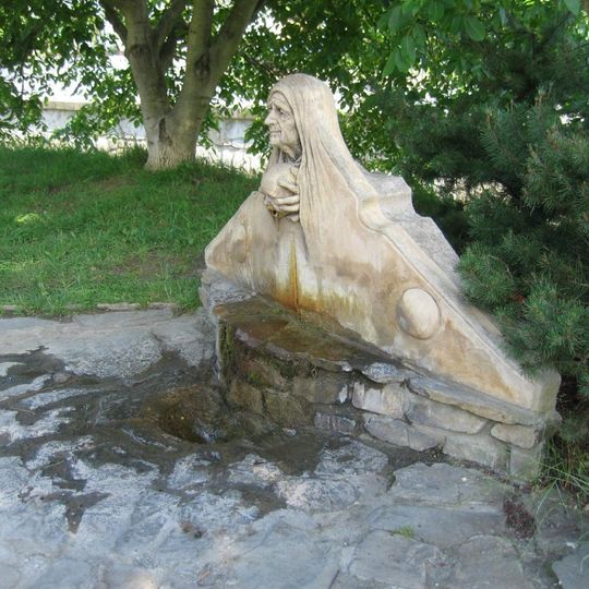 Plastika nad pramenem kyselky ve středu obce