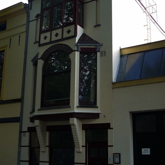 Blokvormig pand, geheel gepleisterd, met verdieping en mezzanino onder flauwhellend, met pannen gedekt schilddak