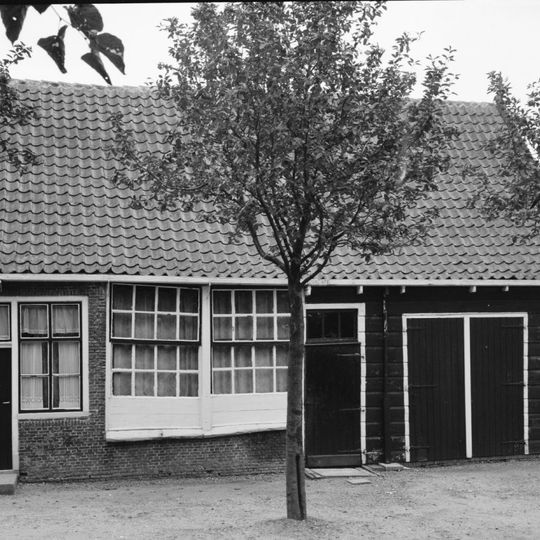 Dwarspand, langs gevel met schuiframen met houten schuurtje