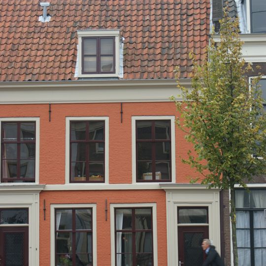 Rechter gedeelte van een pand met verdieping en door pannen gedekt zadeldak, evenwijdig aan de straat. Deuromlijsting midden 19e eeuw, cordonlijst en houten kroonlijst. Stoep met hardstenen paaltjes