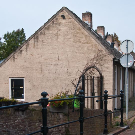 19e eeuws arbeiderswoninkje zonder verdieping onder met blauwe Hollandse pannen gedekt zadeldak, dat doorloopt over de buurpanden