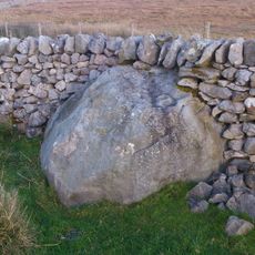 Rock with 30 to 40 cup marks and some groove marks in the wall at the west side of Black Hill Road, 610m ESE of New Dam, Skyreho