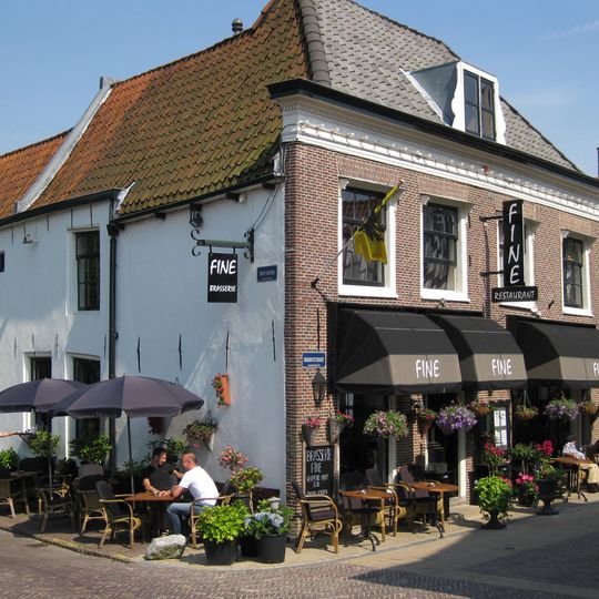 Witgepleisterd hoekhuis met rechte, deels getande kroonlijst