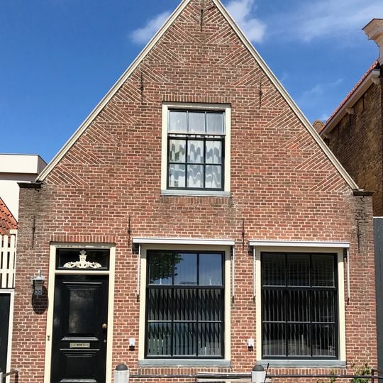 Laag pandje onder zadeldak tegen gepleisterde topgevel