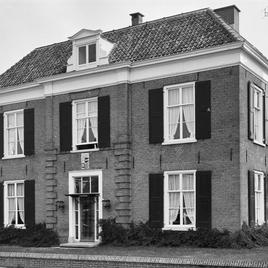Herenhuis met verdieping en omlopend schilddak. Middenrisaliet in de voorgevel. Vensters met luiken en zesruitsschuiframen