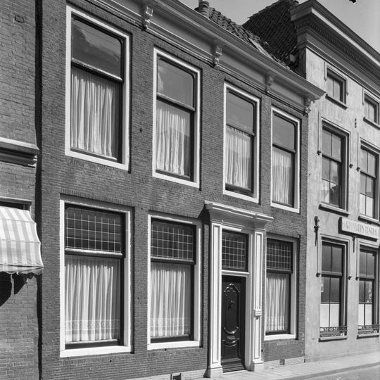 Lijstgevel. Huis van parterre en verdieping. Deuromlijsting met verdiepte pilasters, gesneden deur en consoles onder de kroonlijst Lod. XIV