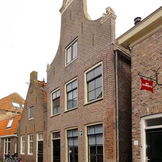 Huis met klokgevel met geveltop met natuurstenen aanzetvoluten en topstuk met jaartalcartouche en schelpversiering