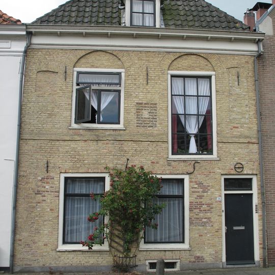 Pand met gevel ontdaan van top en ontlastingsbogen met verdiepte boogvelden boven de vensters van de verdieping