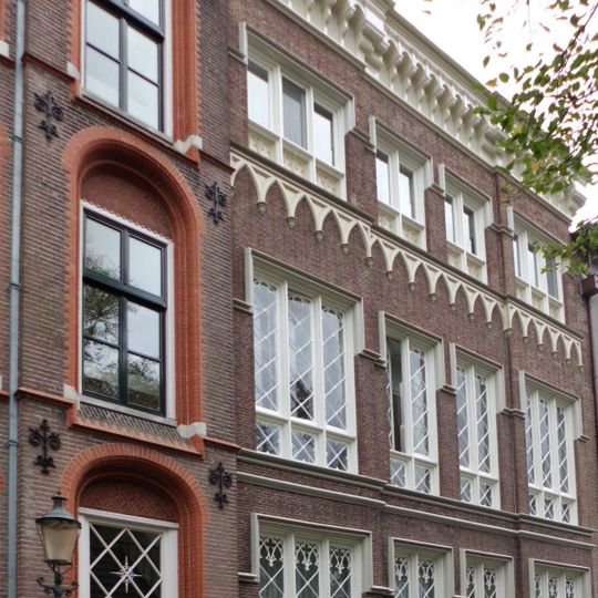 Pand met hoge neogotische gevel gedekt door uitgekraagde kroonlijst. De gevel met banden, spitsboogornamenten versierd. Rechthoekige neogotische banden boven de ramen. Oude roedenverdeling