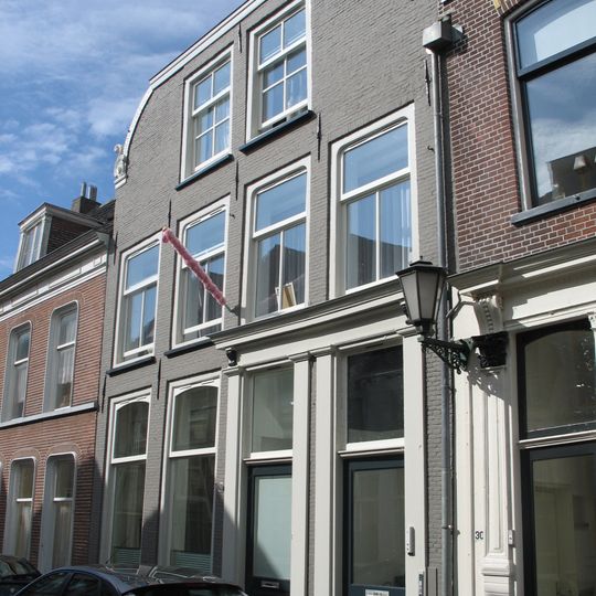 Pand met geverfde klokgevel en natuurstenen aanzetvoluten