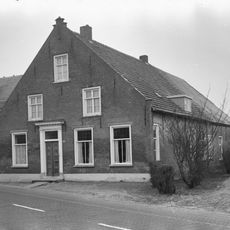 Boerderij van het Langstraatse type, met aan de voorzijde een door trappen en een toppilaster bekroonde tuitgevel; in de verdieping zesdelige schuiframen.