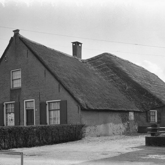 Boerderij met schilderachtig rieten zadeldak, dat zowel het woonhuis als de hogere stal overdekt. Puntgevel met vlechtingen en vensters met luiken en twintig- en zestienruitsroedenverdeling.