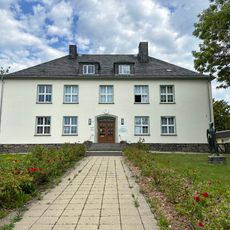 Berufsschule mit einem Wandbild sowie Plastik eines Bauarbeiters in der umgebenden Grünanlage einschließlich Zufahrtstor, Stützmauern und Terrassierung Werdauer Straße 72