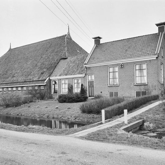 Kop-hals-rompboerderij met zesruitsvensters en schoorstenen aan de topgevels
