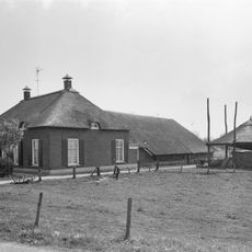 Boerderij met dwars woongedeelte onder rieten schilddak met hoekschoorstenen