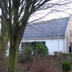 Eenvoudig gepleisterd dwarshuis onder pannen zadeldak