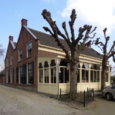 Huis, bestaande uit twee evenwijdige vleugels onder zadeldaken tussen puntgevels. Venster met luiken en zes- en vierruitsschuiframen