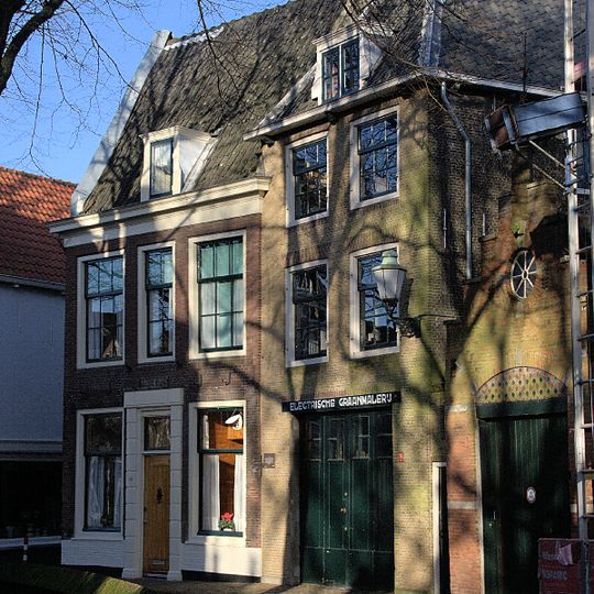 Opgetrokken pakhuis met schilddak, waarin hijsluik. Oude kozijnen met luiken