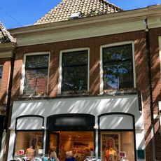 Pand met gedecoreerde rechte kroonlijst onder schilddak met topschoorsteen met bord