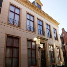 Vijf traveeën breed pand onder schilddak met hoekschoorstenen waarop bord