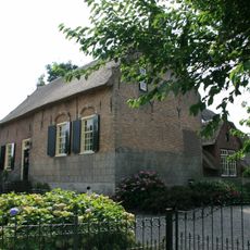 Boerderij met dwars woongedeelte onder rieten zadeldak tussen puntgevels met tussentrappen en vlechtingen.