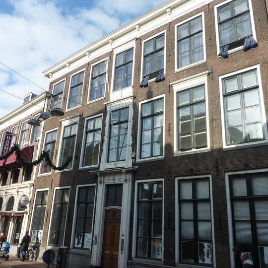 Pand met brede hoge bakstenen gevel met rechte kroonlijst, vensters boven ingang in houten omlijsting