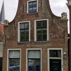 Pand onder zadeldak tegen klokgevel met gebeeldhouwde aanzetkrullen en kroonlijst