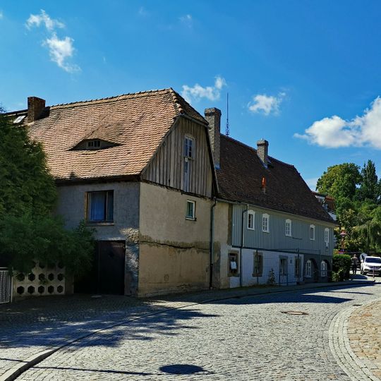 Zwei Wohnhäuser über winkligem Grundriss mit Verbindungsbau als Teil der ehemaligen Schmiede, deren technische Ausstattung sowie rückwärtige Scheune Schulstraße 4, 4a