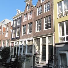 Hoekhuis met hoger opgetrokken voorste stuk onder schilddak. Gepleisterde voorgevel onder rechte lijst