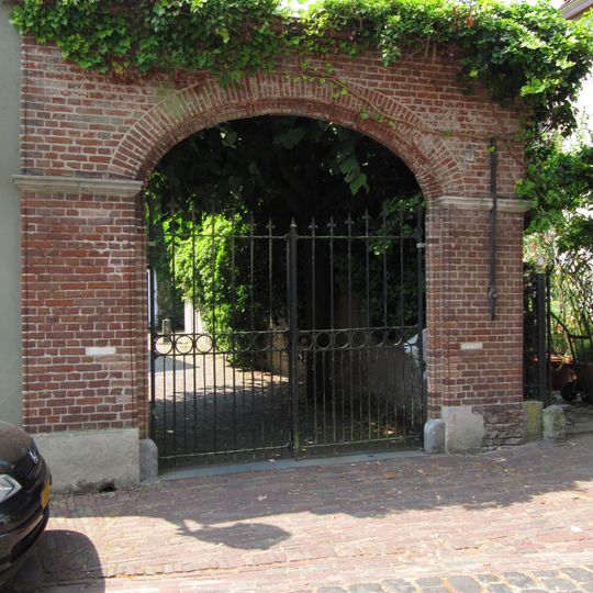 Grote gemetselde poort met pilasters en twee gedenksteentjes