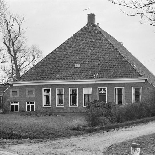 Grote stelphoeve met zes smalle woonhuisvensters ter weerszijden van de ingang, twee melkkeldervensters met siernissen en met stookhut